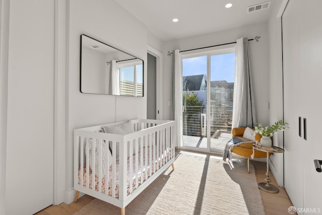 bedroom with multiple windows, a mountain view, hardwood / wood-style flooring, and a nursery area