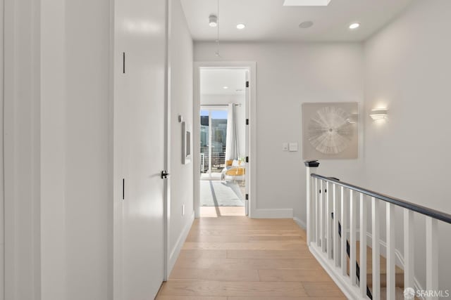 hallway with light hardwood / wood-style flooring and a skylight