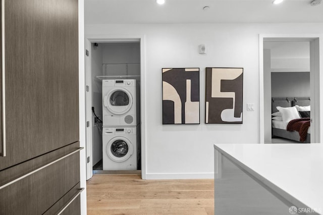 clothes washing area with stacked washer / dryer and light hardwood / wood-style floors