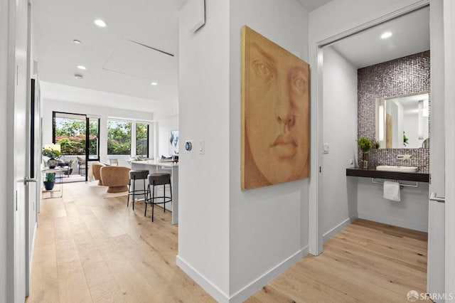 hallway with sink and light hardwood / wood-style flooring