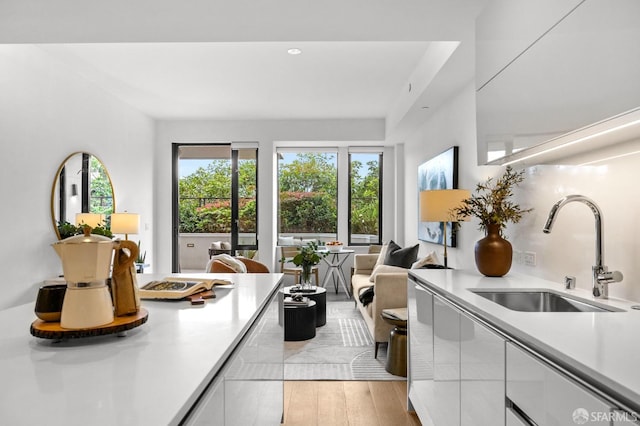 interior space with sink, white cabinets, and light wood-type flooring