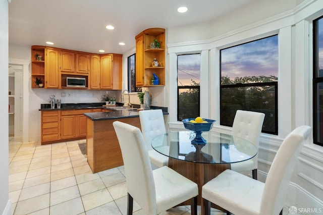 kitchen featuring light tile patterned flooring, decorative backsplash, stainless steel microwave, and sink