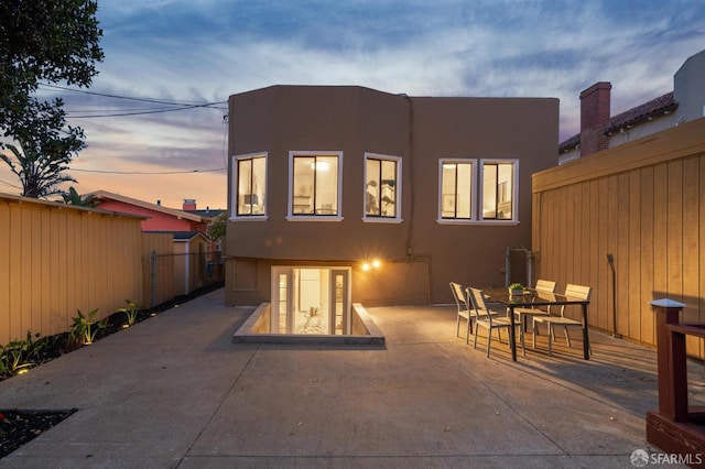 back house at dusk featuring a patio