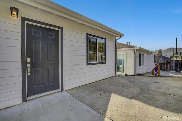 view of exterior entry with a patio area and fence