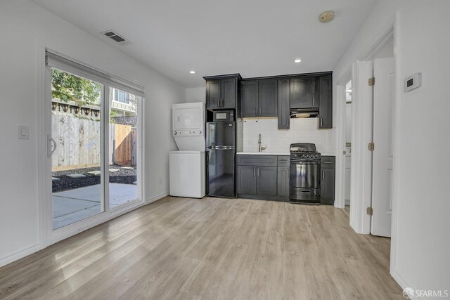 kitchen with stacked washer and dryer, backsplash, under cabinet range hood, visible vents, and black appliances
