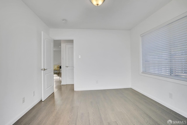 spare room with baseboards and wood finished floors