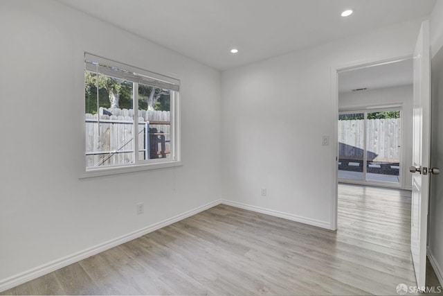 empty room featuring wood finished floors, recessed lighting, baseboards, and a wealth of natural light
