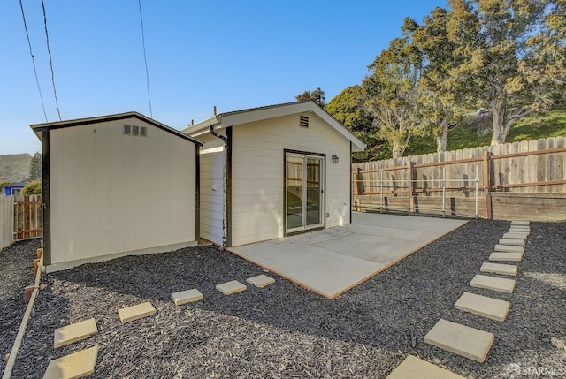 rear view of house with a patio area, a fenced backyard, and an outbuilding