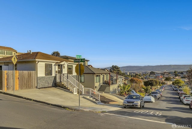 view of front of home featuring fence, a residential view, and a mountain view