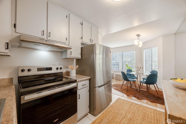 kitchen with appliances with stainless steel finishes, decorative light fixtures, light tile patterned floors, and white cabinets