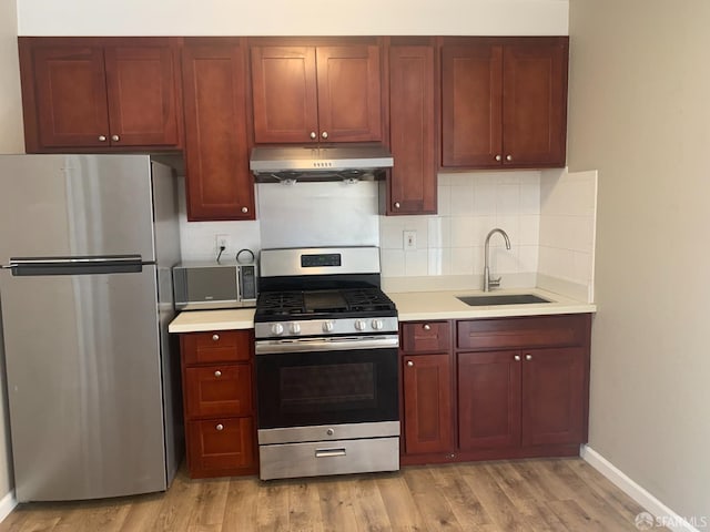 3-5 Sonoma St, San Francisco, CA 94133 - kitchen featuring appliances with stainless steel finishes, under cabinet range hood, a sink, and light wood finished floors