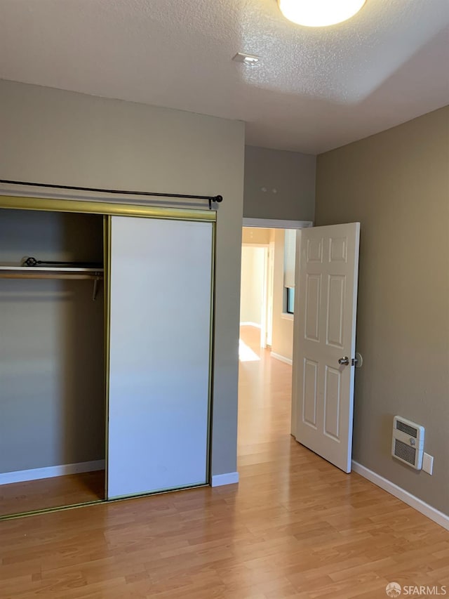 3-5 Sonoma St, San Francisco, CA 94133 - unfurnished bedroom featuring light wood finished floors, baseboards, a textured ceiling, a closet, and heating unit