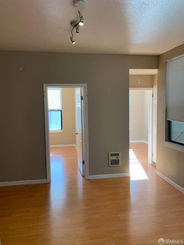 3-5 Sonoma St, San Francisco, CA 94133 - unfurnished room featuring a textured ceiling, light wood-type flooring, heating unit, baseboards, and track lighting