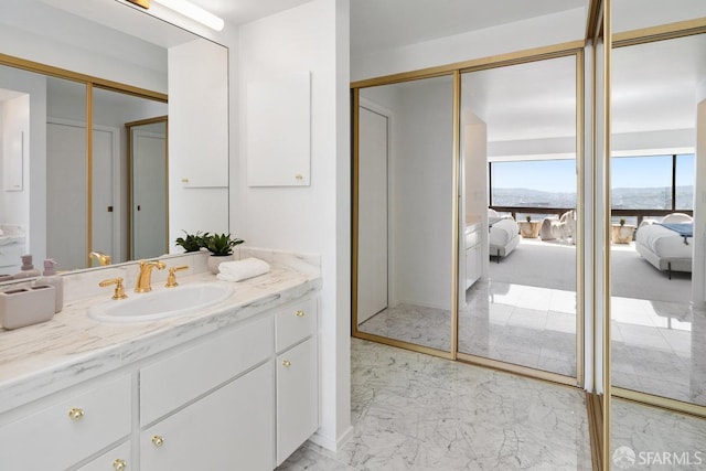 ensuite bathroom with marble finish floor, ensuite bath, and vanity