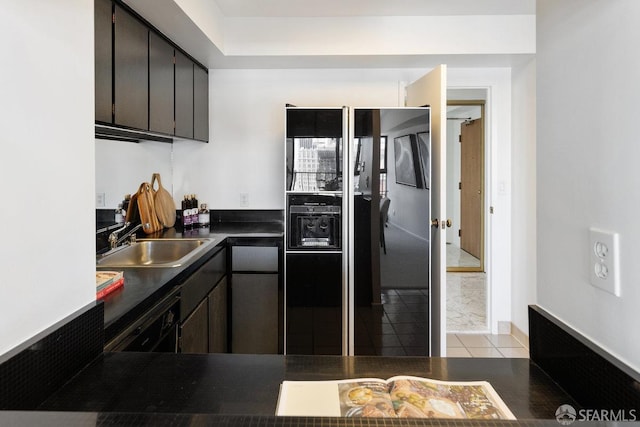 kitchen with a sink, dark countertops, black appliances, and light tile patterned flooring