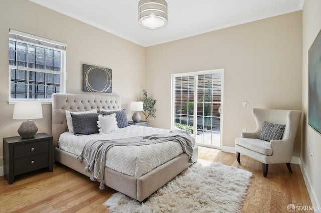 bedroom with access to outside, crown molding, wood finished floors, and baseboards
