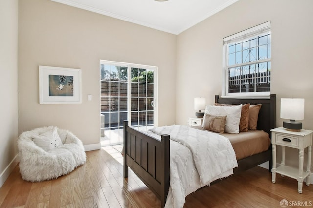bedroom with access to outside, wood finished floors, crown molding, and baseboards
