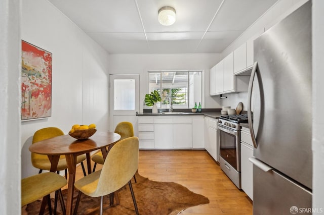 32-34 Gough St, San Francisco, CA 94103 - kitchen featuring appliances with stainless steel finishes, dark countertops, light wood-type flooring, and white cabinetry