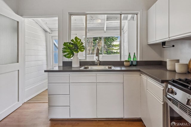 32-34 Gough St, San Francisco, CA 94103 - kitchen featuring a sink, white cabinetry, dark countertops, light wood-style flooring, and gas stove