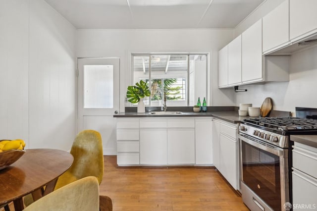 32-34 Gough St, San Francisco, CA 94103 - kitchen with gas stove, light wood finished floors, a sink, dark countertops, and white cabinetry