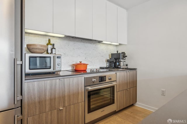 kitchen featuring decorative backsplash, dark countertops, modern cabinets, and appliances with stainless steel finishes