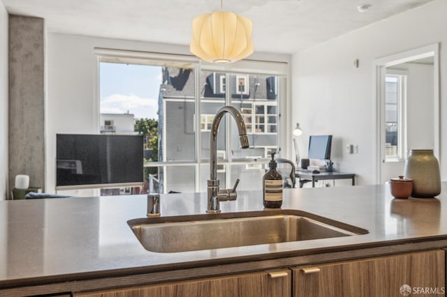 kitchen with hanging light fixtures, brown cabinets, and a sink