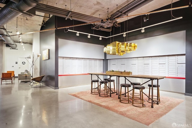 dining area featuring rail lighting, finished concrete flooring, a high ceiling, and baseboards