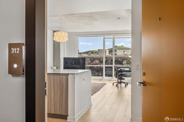 interior space with decorative light fixtures, light wood-style floors, and modern cabinets