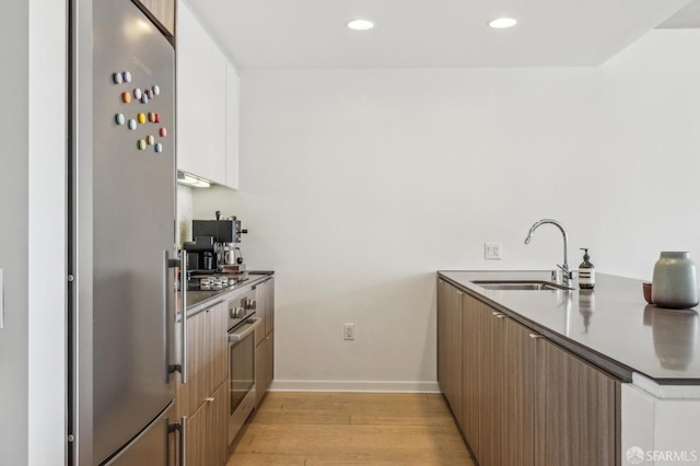 kitchen with recessed lighting, light wood-style flooring, appliances with stainless steel finishes, modern cabinets, and a sink