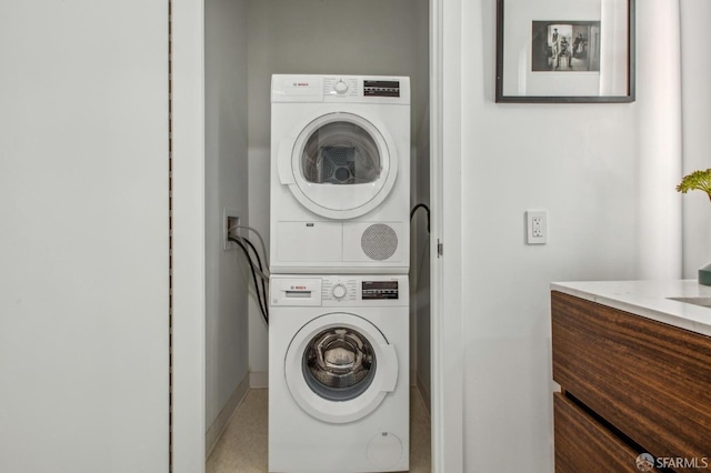 washroom featuring baseboards and stacked washer / drying machine