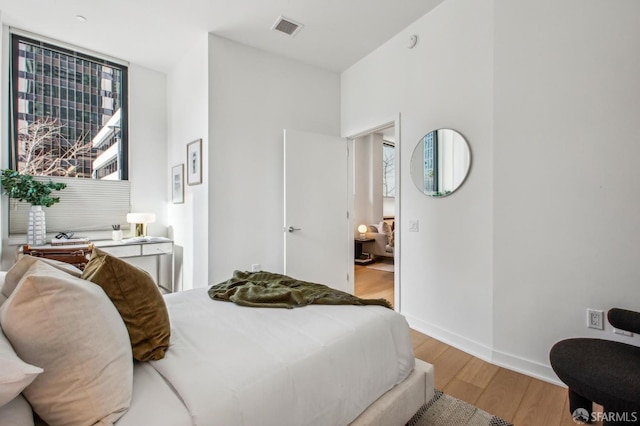 bedroom featuring visible vents, light wood-style flooring, and baseboards