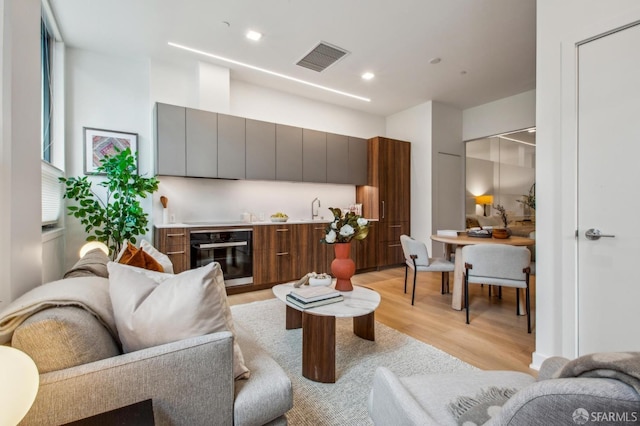 living room with light wood-style floors, recessed lighting, bar area, and visible vents