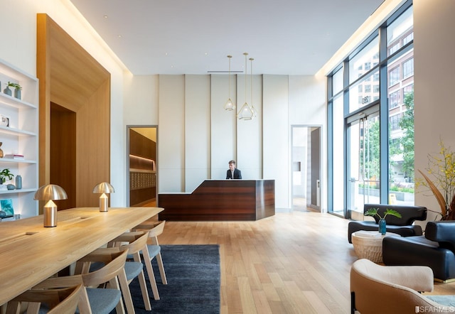 dining area featuring built in shelves, light wood-type flooring, and a high ceiling