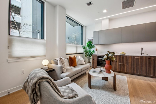 living area with baseboards, visible vents, and light wood finished floors