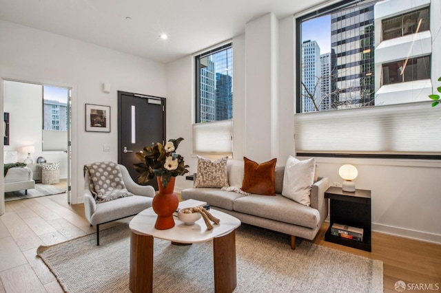 sitting room featuring light wood-type flooring, baseboards, a city view, and recessed lighting