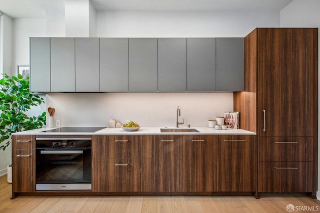 kitchen with black appliances, modern cabinets, a sink, and light countertops