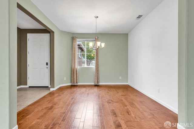 unfurnished dining area with a notable chandelier and light hardwood / wood-style floors