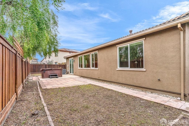 rear view of house with a hot tub and a patio