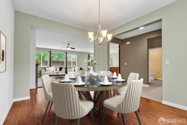 dining room with hardwood / wood-style flooring and ceiling fan with notable chandelier