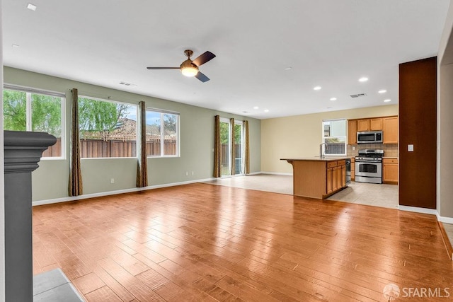 unfurnished living room featuring sink, ceiling fan, and light hardwood / wood-style flooring