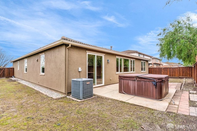 rear view of house with a yard, a hot tub, a patio, and central air condition unit