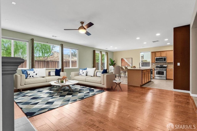 living room with sink, ceiling fan, and light hardwood / wood-style flooring