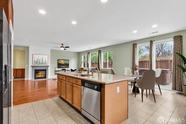 kitchen featuring light tile patterned flooring, an island with sink, sink, ceiling fan, and stainless steel appliances