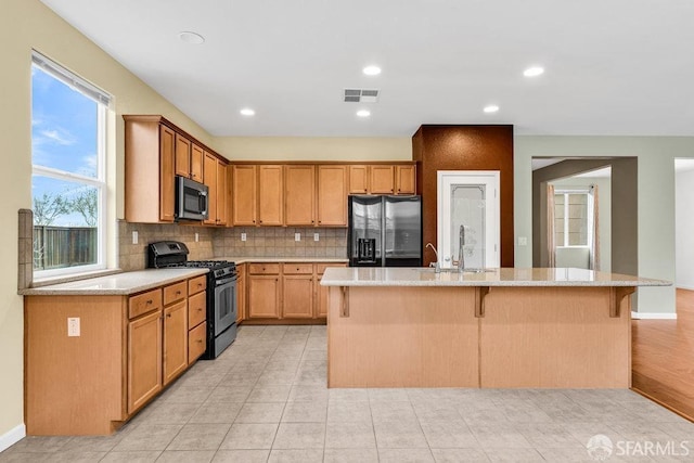 kitchen featuring stainless steel appliances, a kitchen bar, sink, and a center island with sink