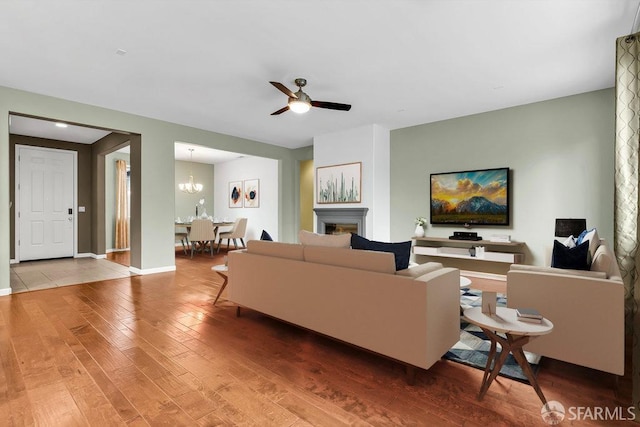 living room featuring ceiling fan with notable chandelier and wood-type flooring