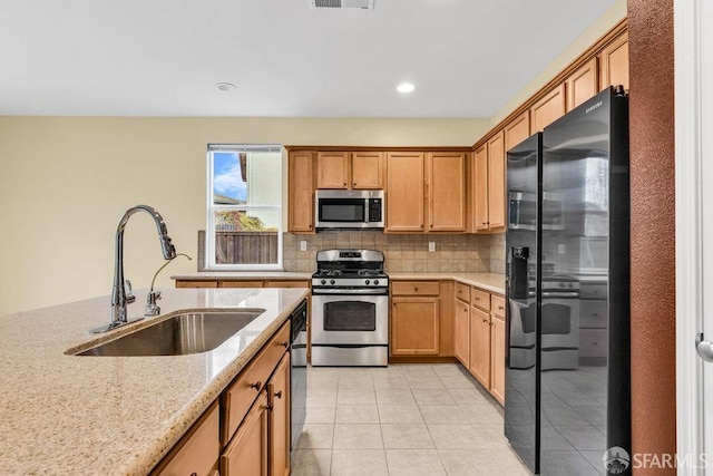 kitchen featuring light tile patterned flooring, sink, backsplash, light stone counters, and black appliances