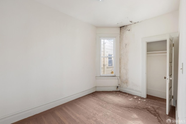 unfurnished bedroom featuring a closet, baseboards, and wood finished floors