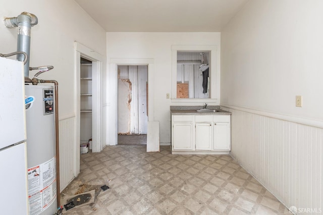 bathroom featuring tile patterned floors, a wainscoted wall, water heater, and vanity