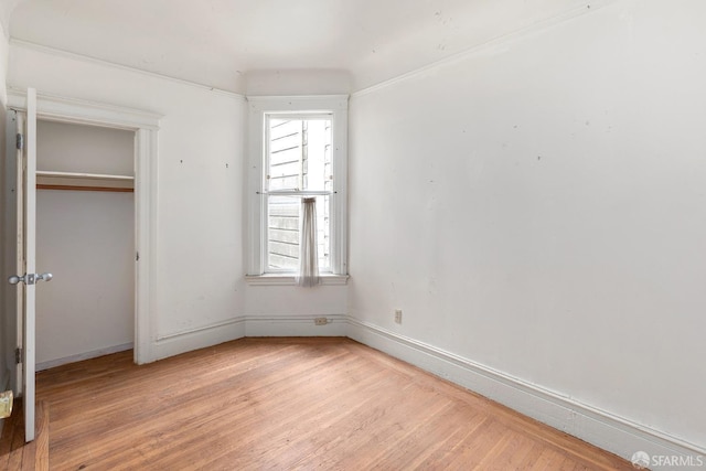 unfurnished bedroom with light wood finished floors, a closet, and baseboards