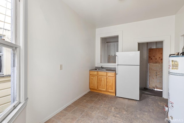 kitchen with a sink, baseboards, water heater, and freestanding refrigerator